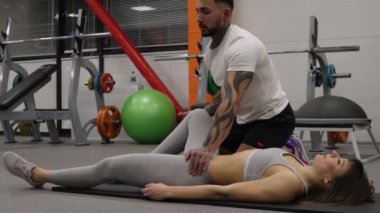 Spor salonundaki spor kadının bacaklarını açan kişisel antrenör.