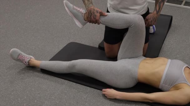 Personlig tränare stretching ben idrottskvinna i gymmet — Stockvideo