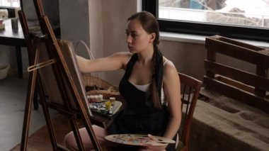 Işıklı ev stüdyosunda resim yapan sakin bir kadın