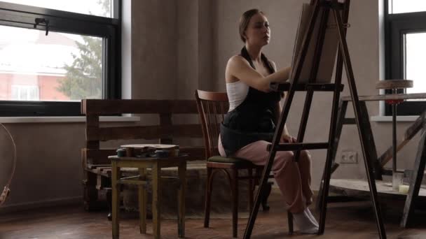 Спокійна жінка малює в світлій домашній студії — стокове відео