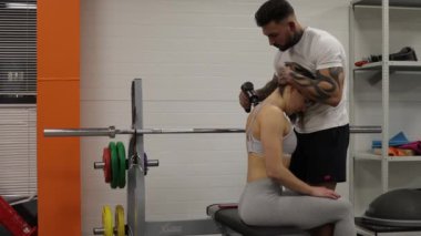 Spor salonundaki spor kadının bacaklarını açan kişisel antrenör.