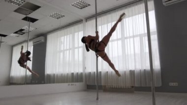 Stüdyoda direğin üstünde dans eden esnek bir kadın.