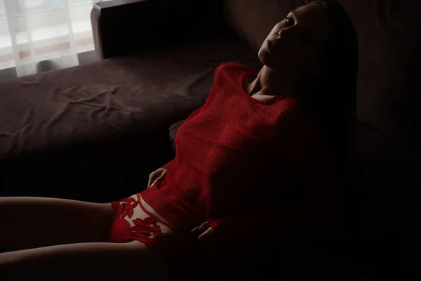 穿着红色针织毛衣和性感花边红内裤躺在床上的性感年轻女性的高角侧视图 — 图库照片