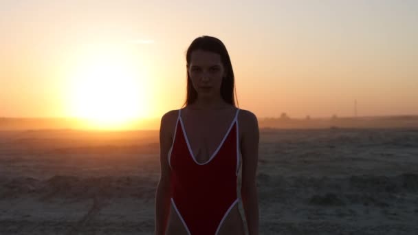 Сексуальна жінка в купальнику ходить уздовж пляжу на заході сонця — стокове відео