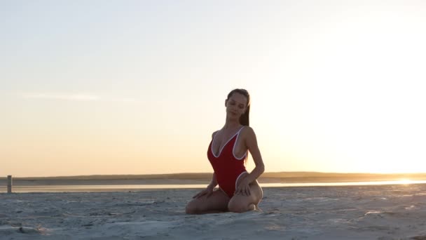 Mujer delgada en traje de baño sexy en la orilla del mar al atardecer — Vídeos de Stock