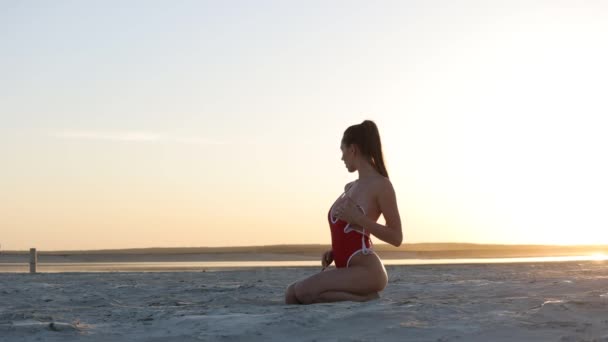 Slim woman in sexy swimsuit on seashore at sunset — Αρχείο Βίντεο