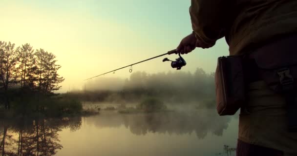 Homem irreconhecível pesca no lago ao amanhecer — Vídeo de Stock