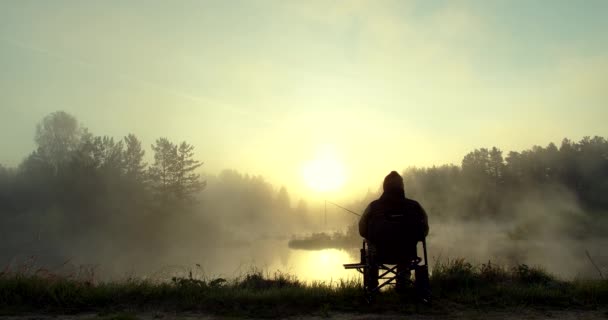 Unrecognizable man fishing in lake at dawn — Stock Video