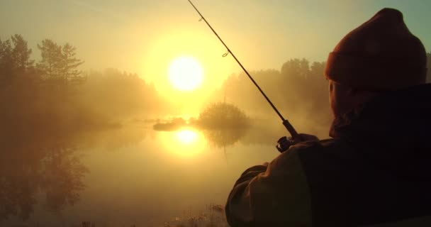 Homme méconnaissable pêche dans le lac à l'aube — Video