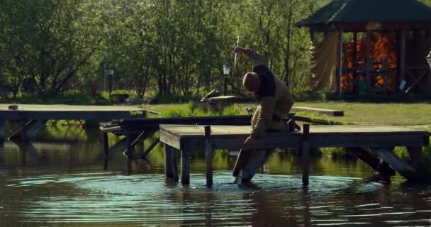 Homem pesca no cais de madeira perto do lago — Vídeo de Stock