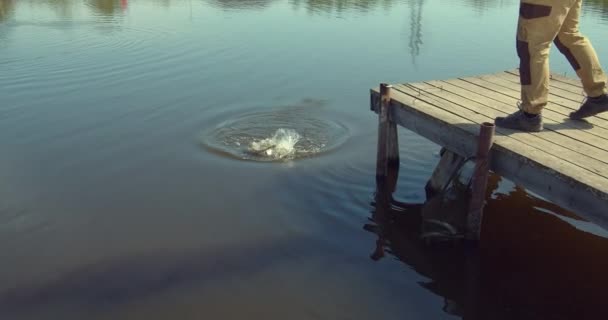 Uomo pesca sul molo di legno vicino al lago — Video Stock