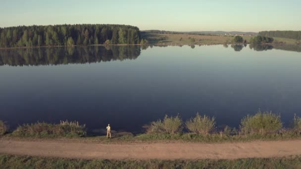 Hombre pescando en muelle de madera cerca del lago — Vídeo de stock