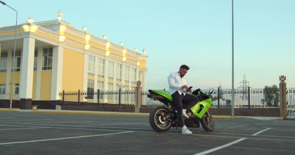 Hombre sentado en motocicleta y el uso de teléfonos inteligentes en la ciudad — Vídeos de Stock