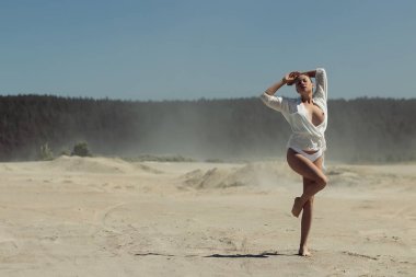 Beyaz bluzlu çekici genç kadın manken çıplak göğüs gözler kapalı ve kollar havada dururken yaz mevsiminde mavi gökyüzüne karşı özgürlük ve güneş ışığının tadını çıkarıyor.