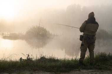 Sabahın erken saatlerinde gölün kıyısında duran ve balık tutan isimsiz balıkçıya bakıyorum.