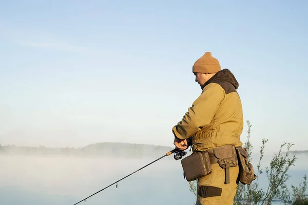 在雾蒙蒙的清晨 一个匿名渔民站在池塘岸边钓鱼的背影 — 图库照片