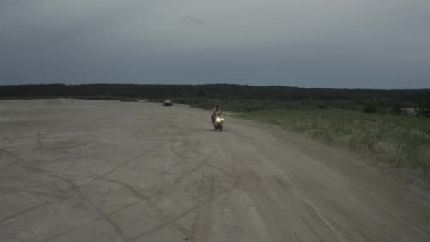 Güzel genç bir çift, gün batımında plajda motosiklet sürüyor. — Stok video