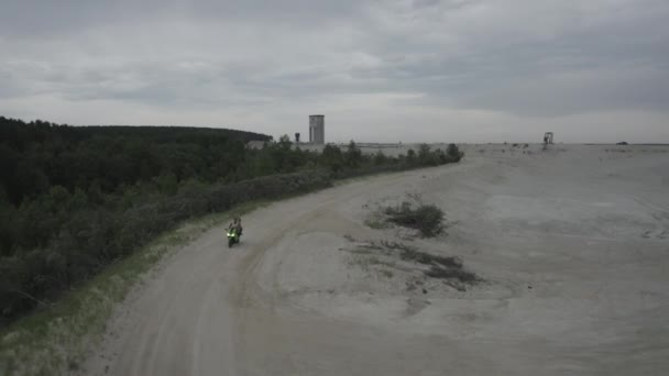 Ein schönes junges Paar, Mann und Frau, fährt während des Sonnenuntergangs gemeinsam auf einem Motorrad am Strand — Stockvideo