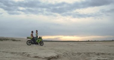 Sahilde motosiklet süren şık bir çift.