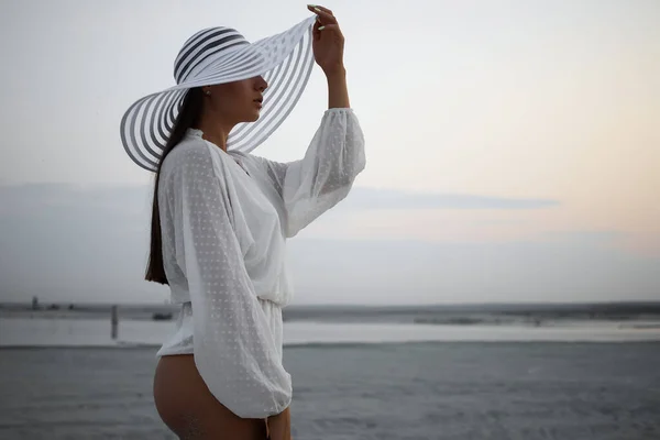 Tanga Bikinili Dantelli Tişörtlü Plaj Şapkalı Alacakaranlıkta Kıyıda Duran Çekici — Stok fotoğraf