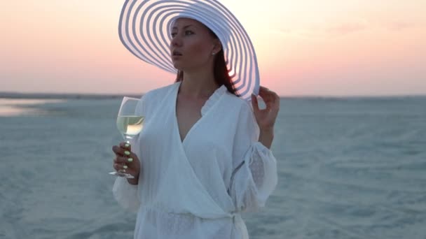 Elegante mujer con copa de vino descansando en la playa al atardecer — Vídeos de Stock