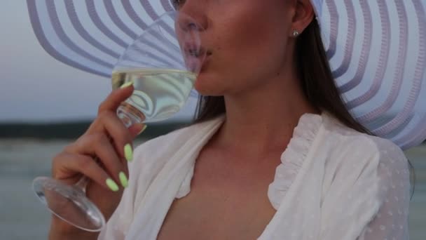 Elegáns nő egy pohár bor pihen a strandon naplementekor — Stock videók