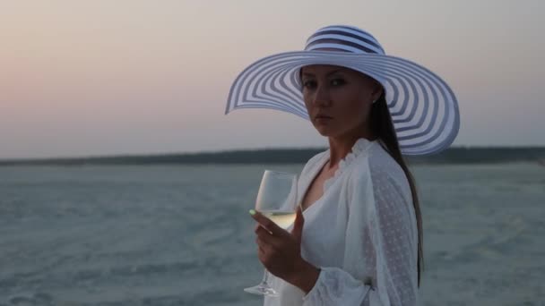Elegante donna con bicchiere di vino che riposa sulla spiaggia al tramonto — Video Stock