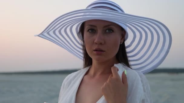Elegante vrouw met een glas wijn rustend op het strand bij zonsondergang — Stockvideo