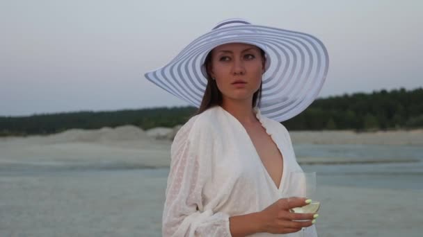 Elegante mujer con copa de vino descansando en la playa al atardecer — Vídeos de Stock