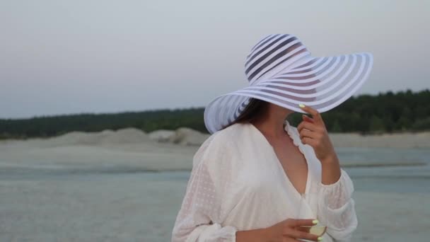 Elegante mujer con copa de vino descansando en la playa al atardecer — Vídeos de Stock