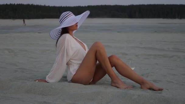 Stijlvolle vrouw met hoed ontspannen op het strand — Stockvideo