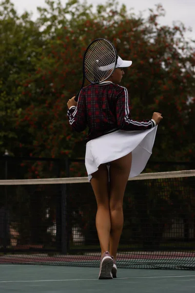 背景色の官能的な女性持ち上げる白いスカートとショー完璧なお尻ながら周りに回転テニスコートで郊外 — ストック写真