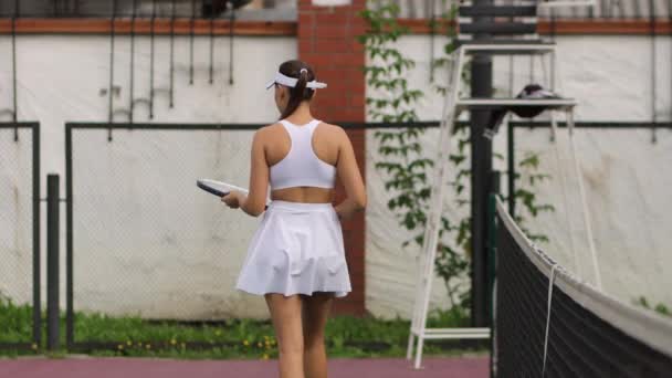 Привлекательная женщина играет в теннис на корте — стоковое видео