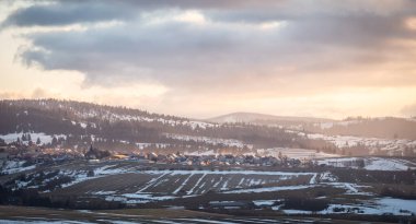 Tepeler arasında renkli kış günbatımında çekilen küçük bir köy. Orava Bölgesi, Slovakya, Avrupa kırsal manzarası