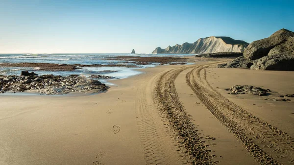 Paisaje de playa con senderos cuádruples en arena que conducen al cabo en la distancia, telón de fondo azul cielo sin nubes. Disparo en Cape Kidnappers Trail, Hawkes Bay — Foto de Stock