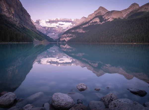 Bellissimo lago alpino che riflette i suoi dintorni, girato durante l'alba al Lago Louise, Banff National Park, Canada — Foto Stock