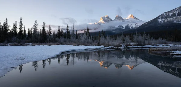 Kanada 'dan gelen panoramik kış gündoğumu görüntüsü, dağa yansıyan su, Three Sisters Mountain, Canmore, Alberta, Kanada