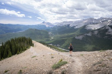 Dağ sırtlarındaki güzel dağ vadisinden uzakta dağ yürüyüşçüsüyle dağ sırtında yürüyen bir kadın, yaz günü Kanada 'nın Nihahi Tepesi' nde vuruldu.