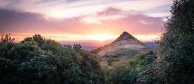 Güneş alışılmadık şekilli bir dağın ardında batıyor. Yeni Zelanda 'daki Christchurch civarındaki Port Hills bölgesinde gün batımı çekiliyor.