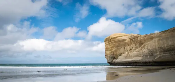 Panoramic seascape with blue sky and sandstone cliff as a main subject. Shot made at Tunnel Beach, Dunedin, Otago Peninsula, New Zealand — Stock Photo, Image