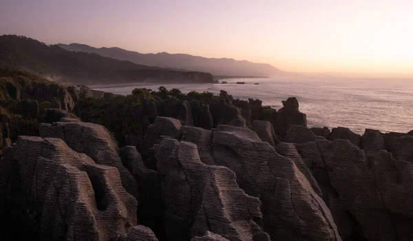 Ungewöhnliche Felsformationen an der Küste des Ozeans, aufgenommen bei Sonnenuntergang, Aufnahme aus Punakaiki Pancake Rocks, Westküste, Neuseeland — Stockfoto