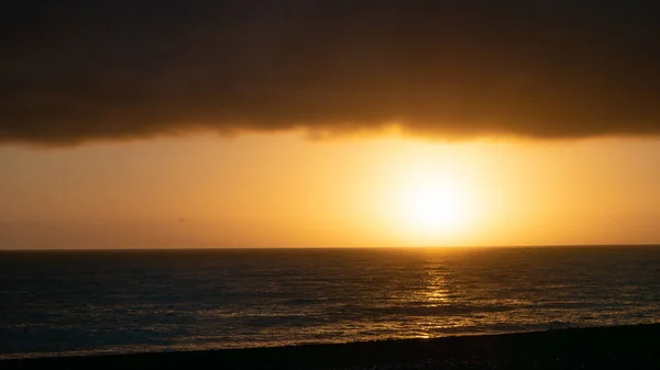 Moody sunrise shot with calm ocean, sun and thick cloud layer in upper third, shot in Kaikoura, New Zealand — Stockfoto