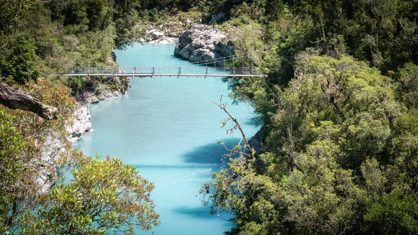 Garganta del río con aguas turquesas y puente oscilante que conduce por encima de ella. Paisaje hecho en el desfiladero de Hokitika, Costa Oeste, Nueva Zelanda — Foto de Stock