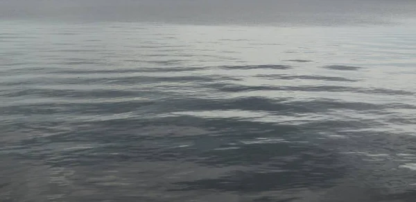 波紋と光沢のある濃い灰色の水の背景 — ストック写真