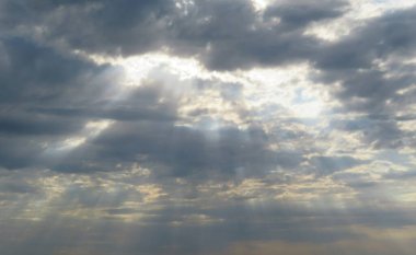 Gün batımında, güneş ışınlarıyla gökyüzünde kara bulutlar.