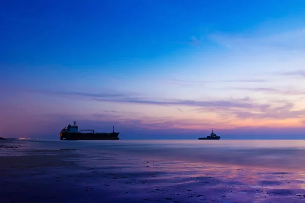 Ship Wreck along the Umm Al Quwain Coast in UAE. A stranded oil tanker vessel on the beach being rescued by another ship. Long exposure shot.