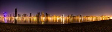 Sharjah Skyscraper ya da Skyline 'ın güzel panoramik çekimi. Al Mamzar Sahili 'nin gece manzarası..