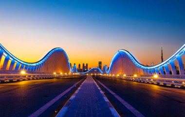 Dubai 'deki Meydan Köprüsü' nün güzel manzarası. Dubai 'deki modern sanatsal köprü. Kıvrımlı mavi ışıkları olan bir köprünün gece mimari çekimi.