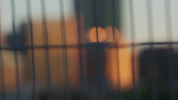 金属製のフェンスと建物の間のラックフォーカス — ストック動画