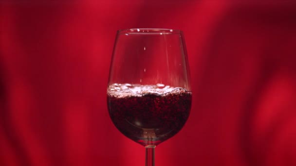 Vino Tinto Una Copa Sobre Fondo Rojo — Vídeo de stock